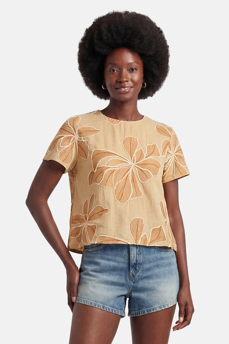 Blouse à manches courtes beige de VERO MODA® avec motifs floraux brodés marron clair, portée sur un short en jean.