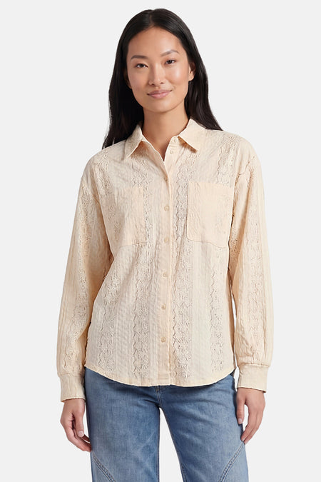 Chemise beige de VERO MODA à motif texturé brodé verticalement, à manches longues et col, avec poches poitrine, portée avec un jean.