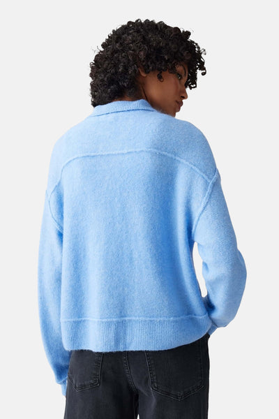 Pull bleu d'OPUS, en maille douce, avec une coupe décontractée et un col classique, porté avec un jean noir, vue de dos.
