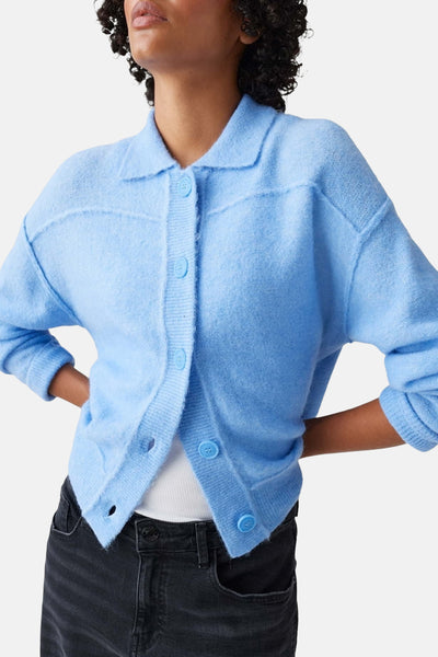 Pull bleu d'OPUS, avec col et boutons, porté avec un jean noir.