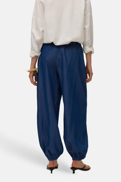Pantalon ample bleu en denim de VERO MODA, porté avec une chemise blanche et des sandales à talons.
