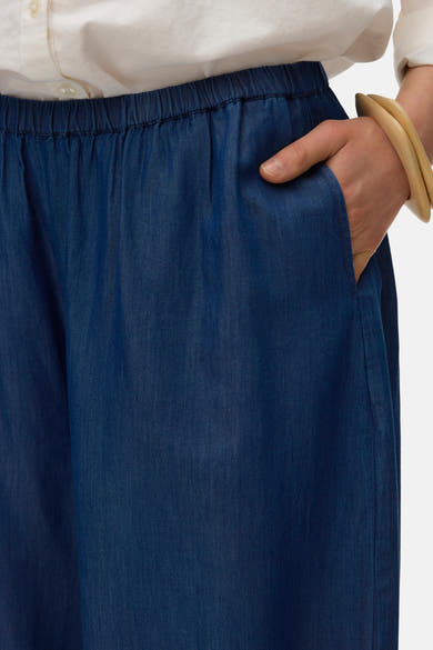 Blauwe broek van VERO MODA, met elastische tailleband en een steekzak, gedragen met een beige armband.