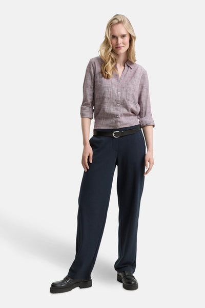 Bordeaux blouse met lange mouwen van Tom Tailor, gedragen met een wijde marineblauwe broek en een zwarte riem.