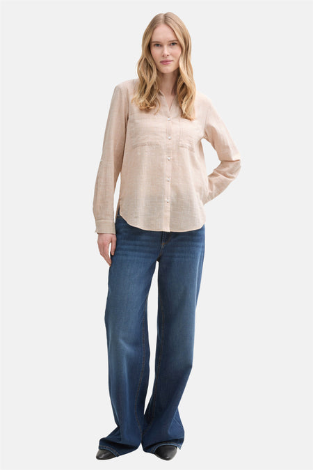 Beige blouse met lange mouwen van Tom Tailor, gedragen met een wijde blauwe jeans en zwarte schoenen.