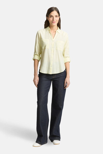 Chemise à manches longues jaune, de Tom Tailor, avec des poches plaquées et des manches retroussées, portée avec un jean bleu foncé.
