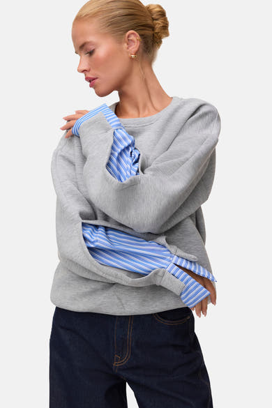 Light grey melange sweatshirt with ribbed cuffs and relaxed fit, worn over blue striped shirt, side view