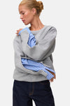 Light grey melange sweatshirt with ribbed cuffs and relaxed fit, worn over blue striped shirt, side view