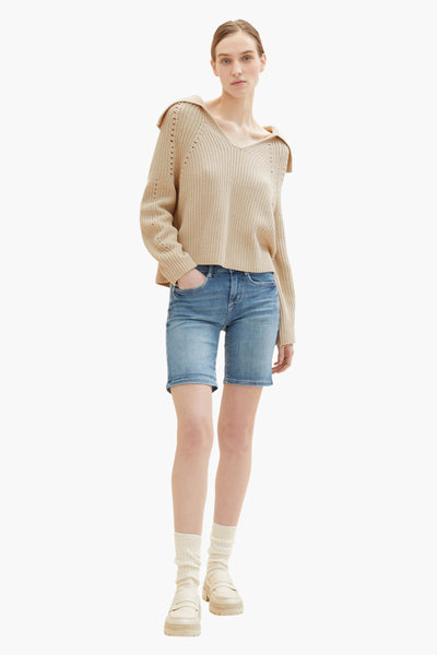 Bermuda bleu de Tom Tailor, porté avec un pull en tricot beige à col large, des chaussettes ivoire et des mocassins.