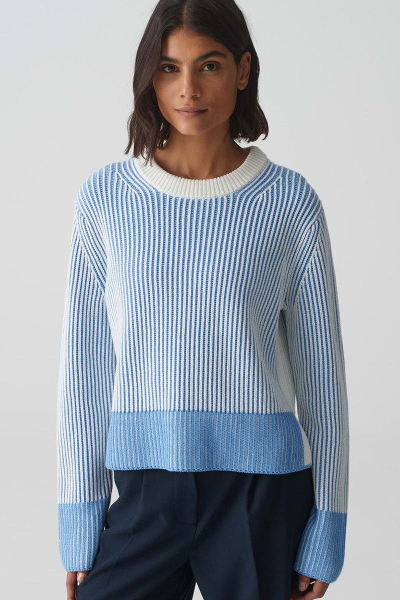Ronde hals trui blauw OPUS, witte en blauwe verticale strepen, gedragen met een marineblauwe broek.