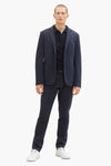 Marineblauwe chino van Tom Tailor, gedragen met een gestreept marineblauw poloshirt en witte sneakers.