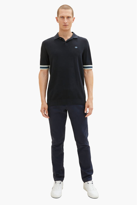 Chino bleu de Tom Tailor, porté avec un polo noir à manches courtes et des baskets blanches.