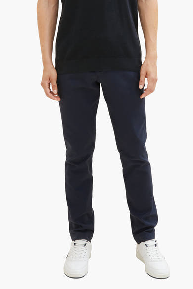 Blauwe chino van Tom Tailor, gedragen met een zwart poloshirt en witte sneakers.