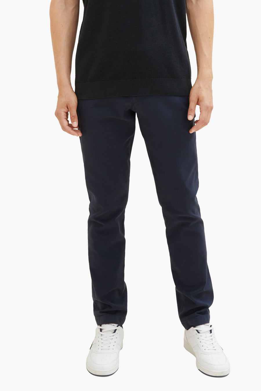 Blauwe chino van Tom Tailor, gedragen met een zwart poloshirt en witte sneakers.