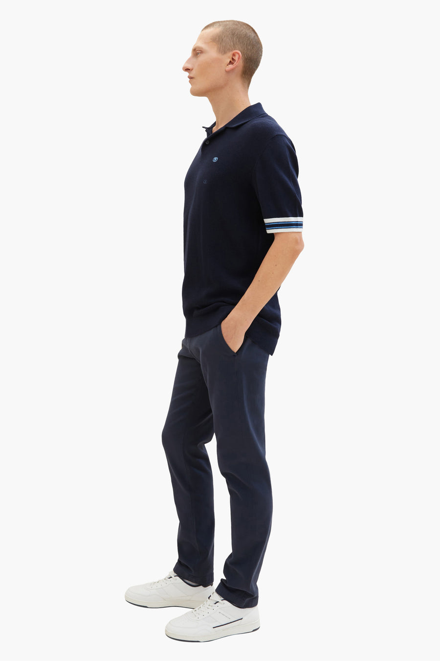 Blauwe chino van Tom Tailor, gedragen met een marineblauw gestreept poloshirt en witte sneakers.