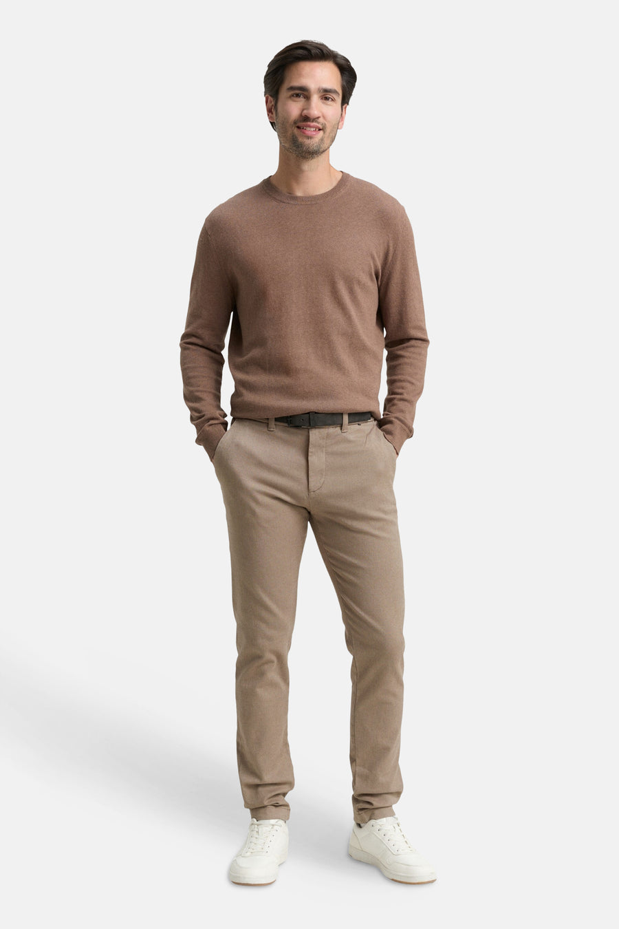 Brown chino pants with slim fit, worn by model in full-length front view, paired with brown sweater and white sneakers.