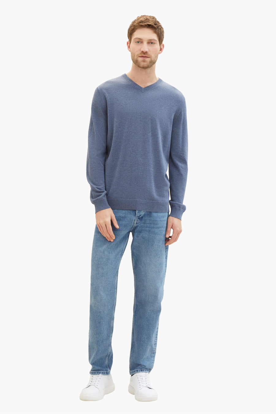 Blauwe V-hals trui van Tom Tailor, gedragen met een lichtblauwe jeans en witte sneakers.
