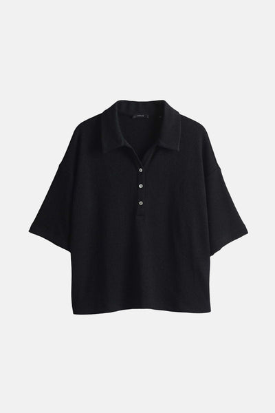 Polo noir à manches courtes par OPUS, avec une texture subtile et une patte de boutonnage minimaliste.
