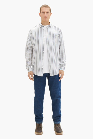 Chemise à manches longues blanche à rayures by Tom Tailor, portée avec un t-shirt blanc et un jean bleu.