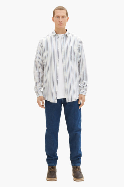 Chemise à manches longues blanche à rayures by Tom Tailor, portée avec un t-shirt blanc et un jean bleu.