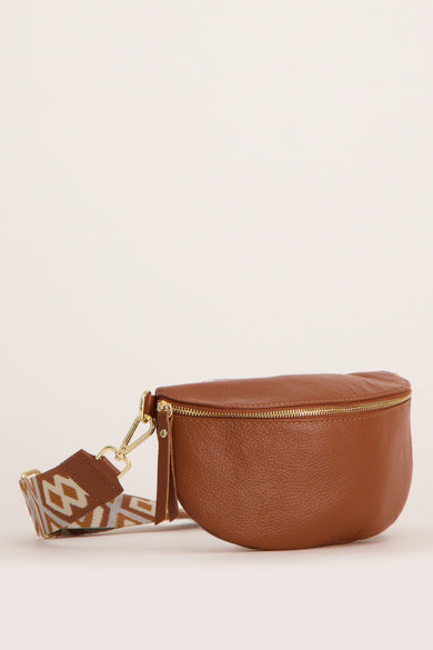 Sac banane marron en cuir Access®, avec une bandoulière à motif géométrique et une fermeture éclair dorée.