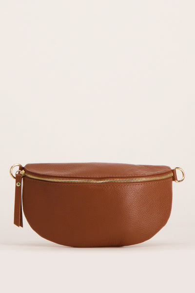 Sac à bandoulière brun en cuir par Access, avec fermeture éclair dorée et tirette décorative.
