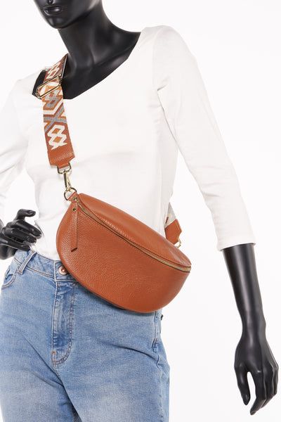 Sac à bandoulière en cuir marron Access®, porté croisé sur un mannequin avec jean et pull blanc.