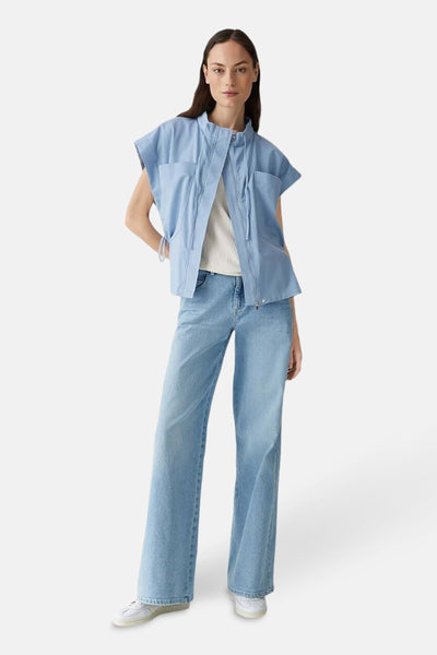 Veste sans manches bleu de OPUS, portée avec un jean large bleu clair et des chaussures blanches.