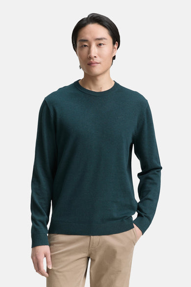 Pull à col rond vert, par Tom Tailor, porté avec un pantalon beige uni.