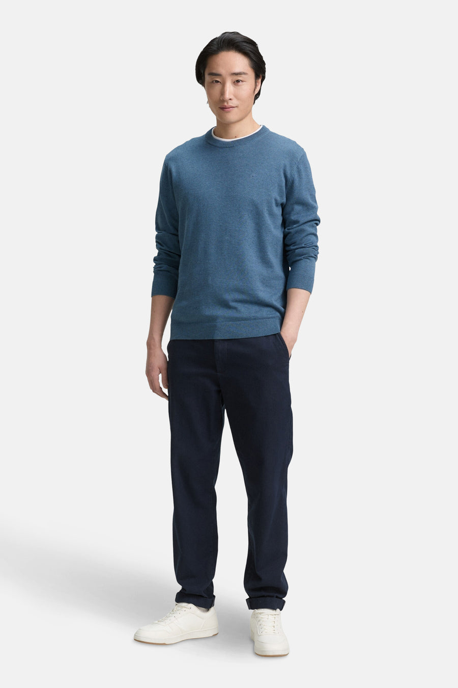 Ronde hals trui blauw van Tom Tailor, gedragen met een donkere broek en witte sneakers.