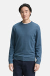 Ronde hals trui blauw van Tom Tailor, gedragen over een wit T-shirt, met een marineblauwe broek.