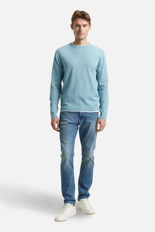 Pull à col rond bleu de Tom Tailor, porté avec un jean et des baskets blanches.
