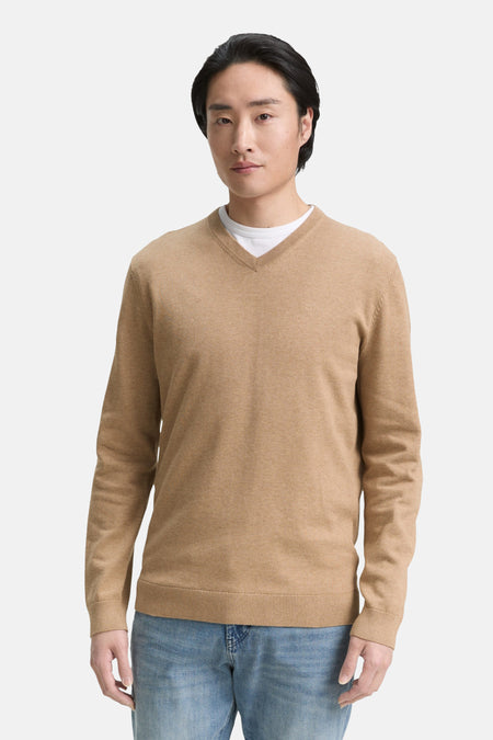 Beige V-hals trui van Tom Tailor, gedragen over een wit T-shirt en een blauwe spijkerbroek.