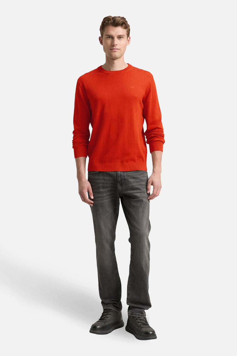 Pull à col rond orange de Tom Tailor, porté avec un jean gris et des chaussures noires.