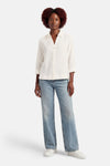 Chemise blanche à manches longues par OPUS, en coton texturé, portée avec un jean ample bleu.
