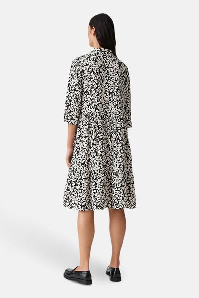 Zwarte jurk met lange mouwen en print van OPUS, met een uitlopende pasvorm en zwarte lakleren schoenen.