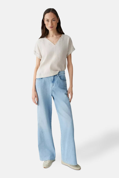 Blouse écru à manches courtes de OPUS, portée avec un jean large bleu clair et des baskets beiges.
