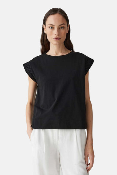Zwart mouwloos topje van OPUS, met uitgesneden details op de schouders, gedragen met een witte broek.