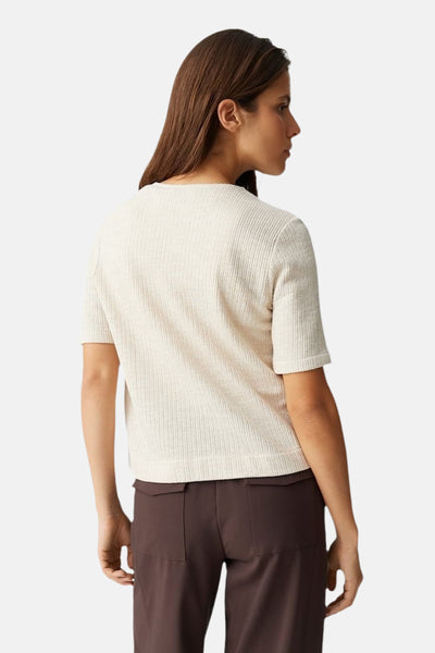 Blouse beige en maille côtelée d'OPUS, avec des manches courtes et portée avec un pantalon marron uni.
