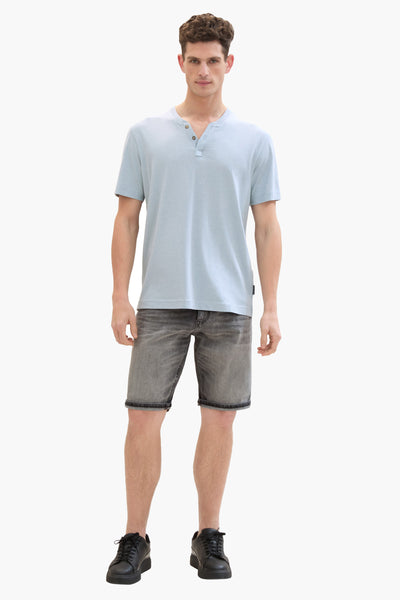 Lichtgrijze spijkerbroek van Tom Tailor, gedragen met een lichtblauw T-shirt en zwarte schoenen.