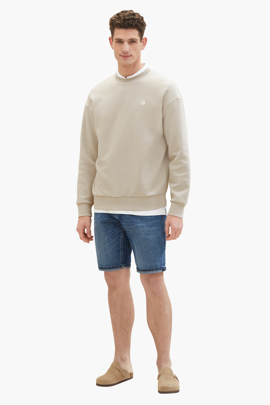 Korte donkerblauwe spijkerbroek van Tom Tailor, gedragen met een beige sweater en suède muiltjes.