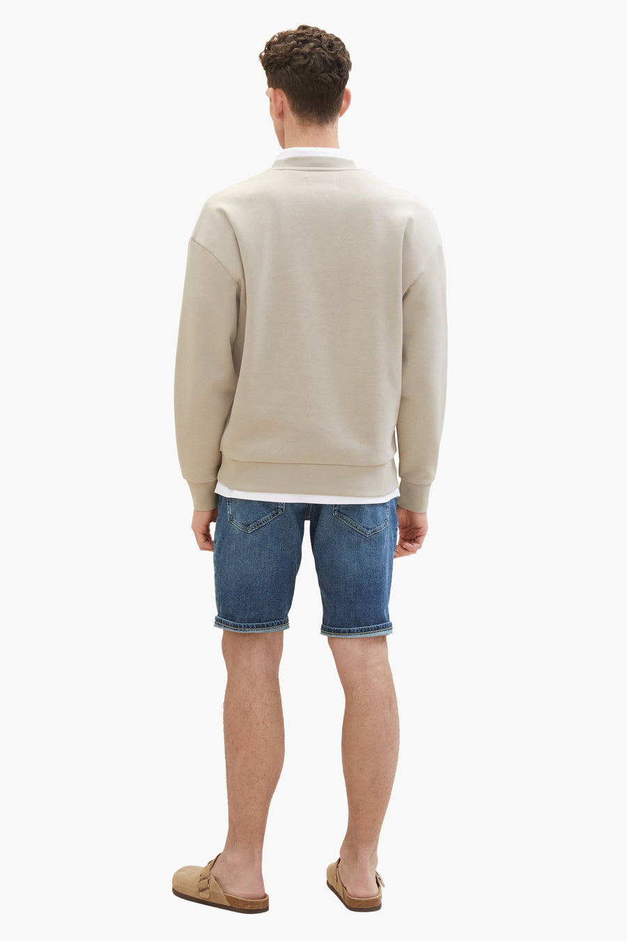 Korte donkerblauwe spijkerbroek van Tom Tailor, gedragen met een beige trui en leren sandalen.