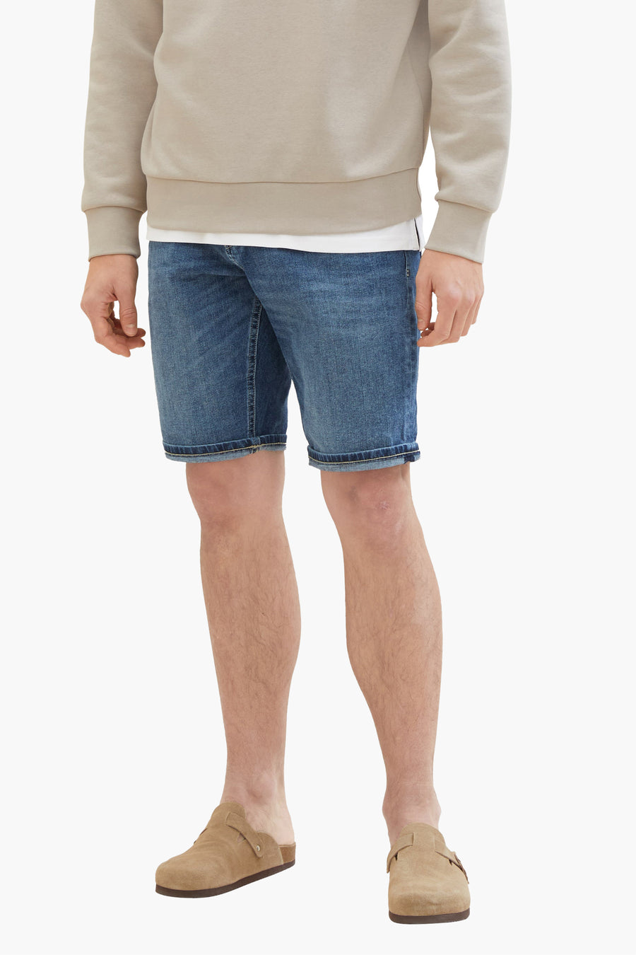 Korte donkerblauwe spijkerbroek van Tom Tailor, gedragen met een beige trui en bruine suède klompen.