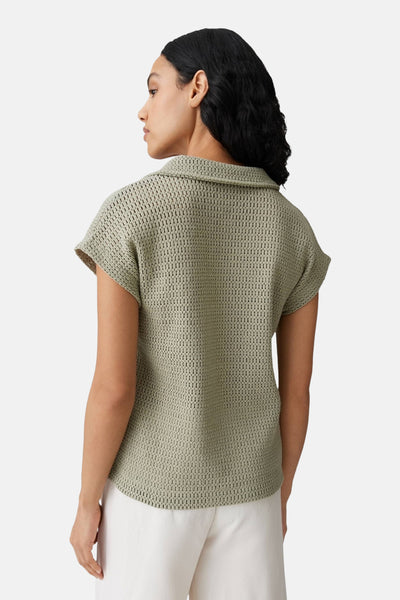 Polo vert de OPUS en maille ajourée à manches courtes, vue de dos, porté avec un pantalon blanc.