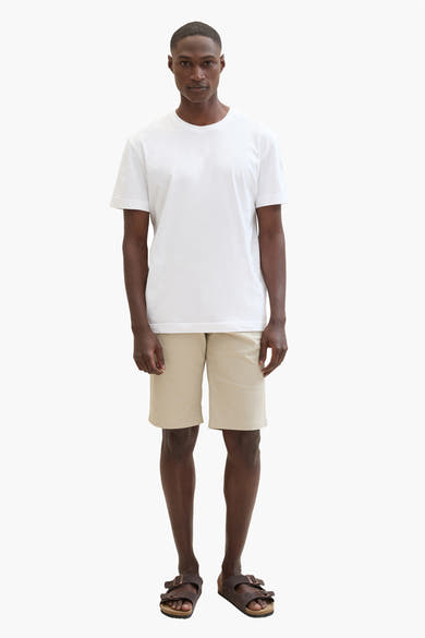 Korte beige short van Tom Tailor, gedragen met een wit T-shirt en bruine sandalen.