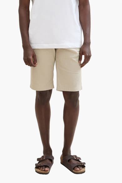 Korte beige short van Tom Tailor, gedragen met een wit T-shirt en bruine sandalen.