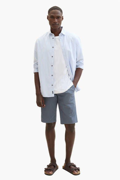 Korte blauwe blazer van Tom Tailor, gedragen met een lichtblauw gestreept overhemd en bruine sandalen.