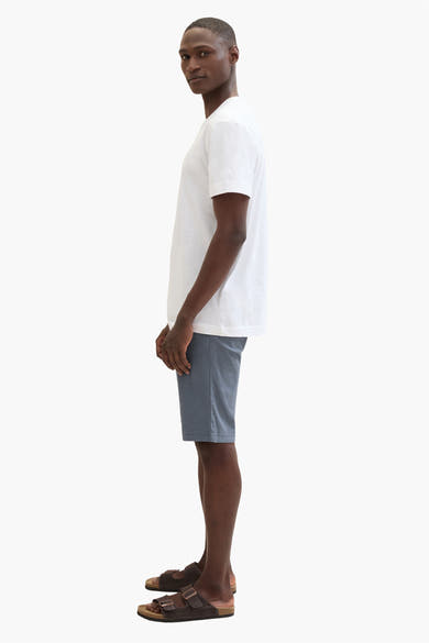 Korte blauwe Tom Tailor short, gedragen met een wit T-shirt en bruine leren sandalen, zijwaarts gezien.