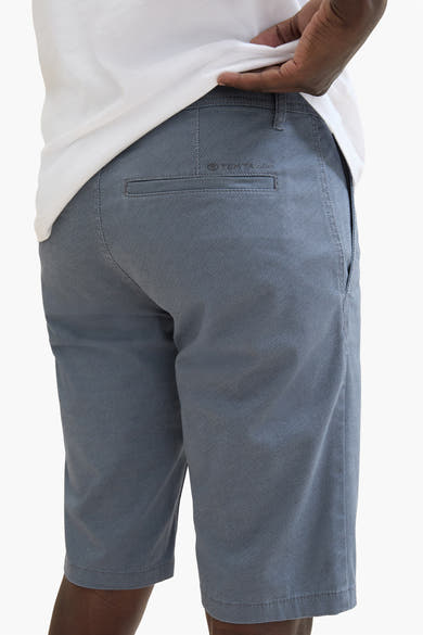 Korte blauwe van Tom Tailor, met een discreet patroon, paspelzak achter, gedragen met een wit T-shirt.