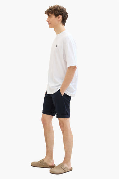 Korte blauwe Tom Tailor short, gedragen met een los wit T-shirt en beige suède muiltjes.
