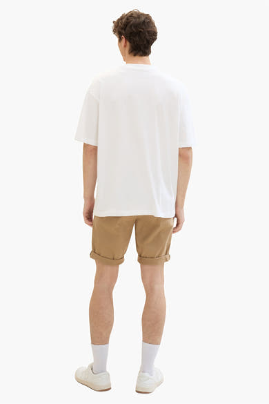 Short beige de Tom Tailor, avec revers, porté avec un t-shirt blanc, des chaussettes et des chaussures blanches.